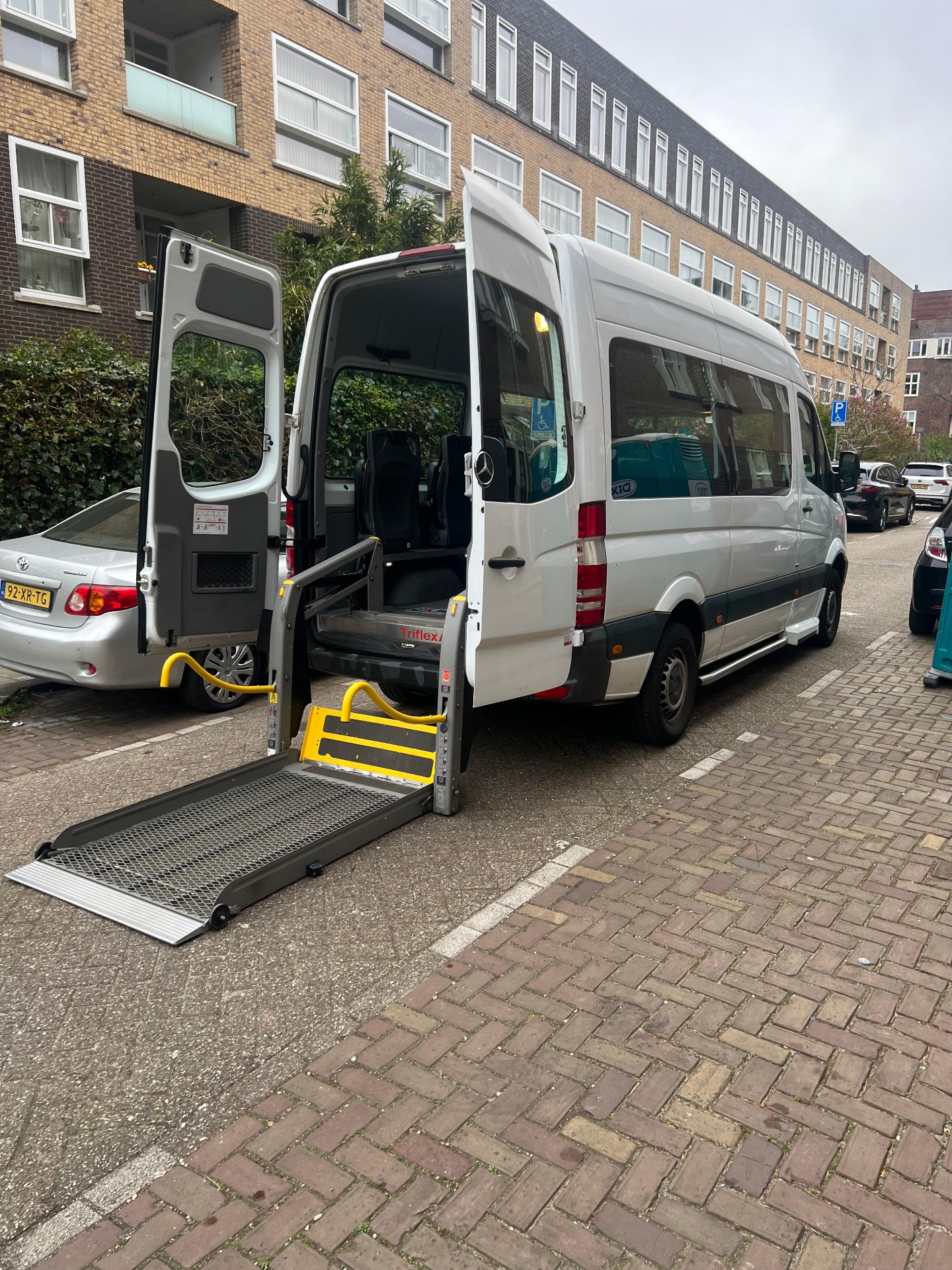 Zijaanzicht van de zorgtaxi met uitgeklapte rolstoellift